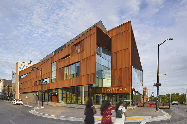 Perspective of a building with angular oxidized steel facade and curtain wall windows.
